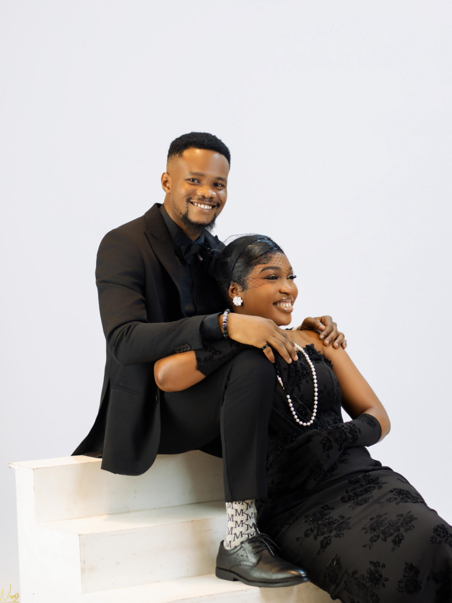 Kent and Iheoma laughing together on white steps in black formal wear