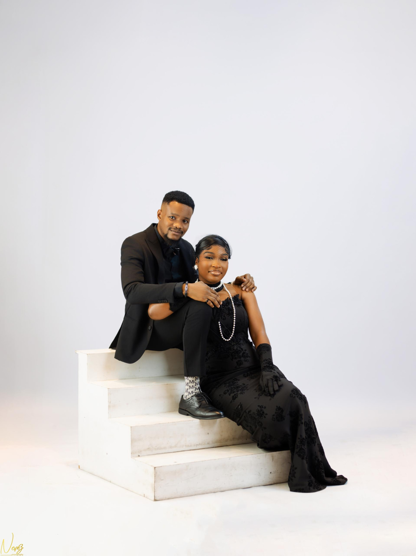 Kent and Iheoma seated on white steps in black formal wear